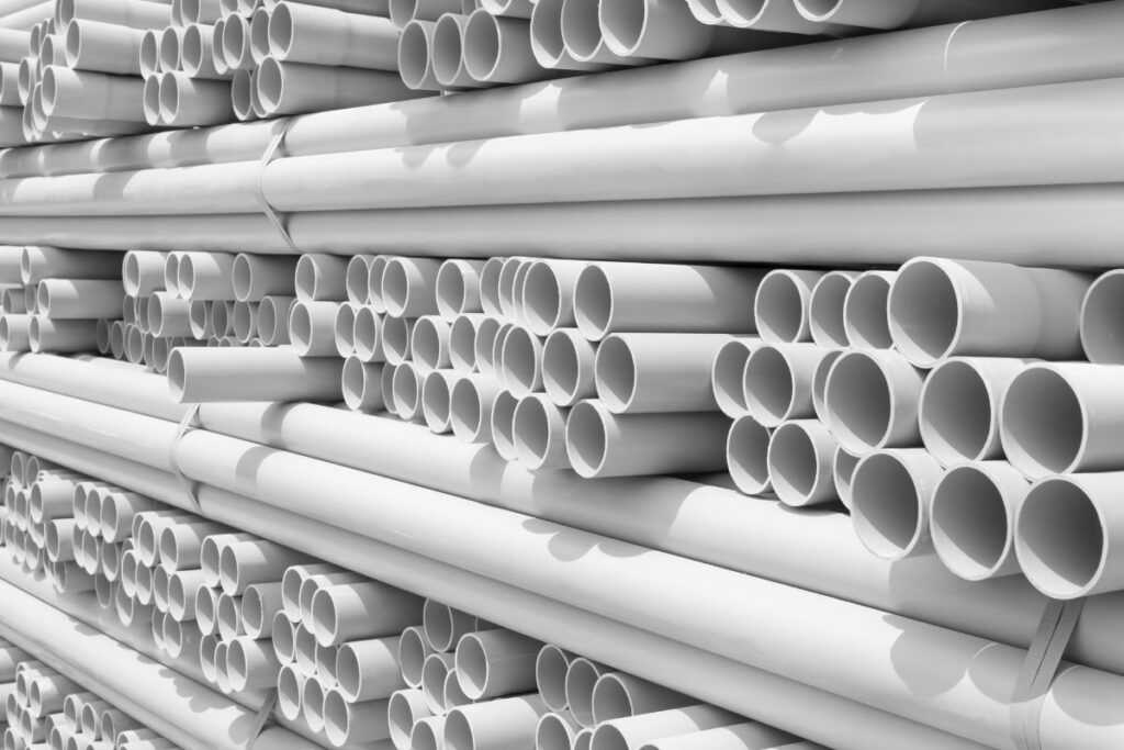 a bundle of white schedule 40 4-inch PVC pipes, commonly used for residential sewer line replacement, hinting at the need for permits and regulations